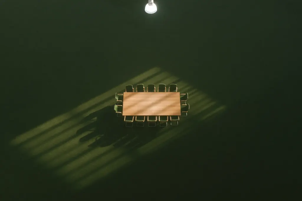 Meeting table from above in a shaft of light in a dark green room