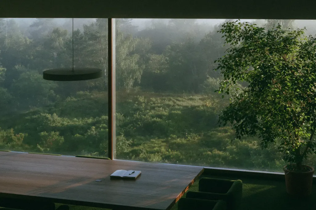 Meeting table by a glass wall overlooking misty forest